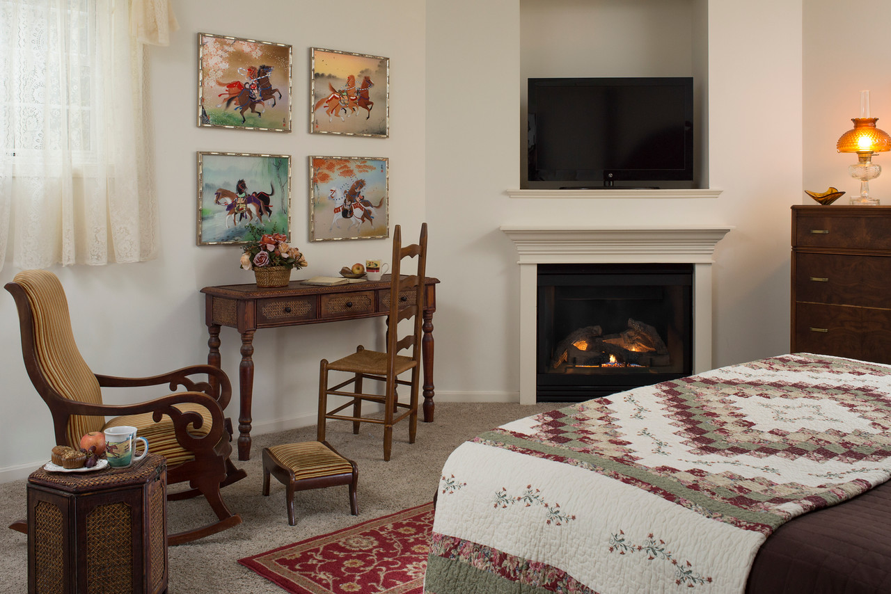 Chair and small desk near fireplace and king size bed