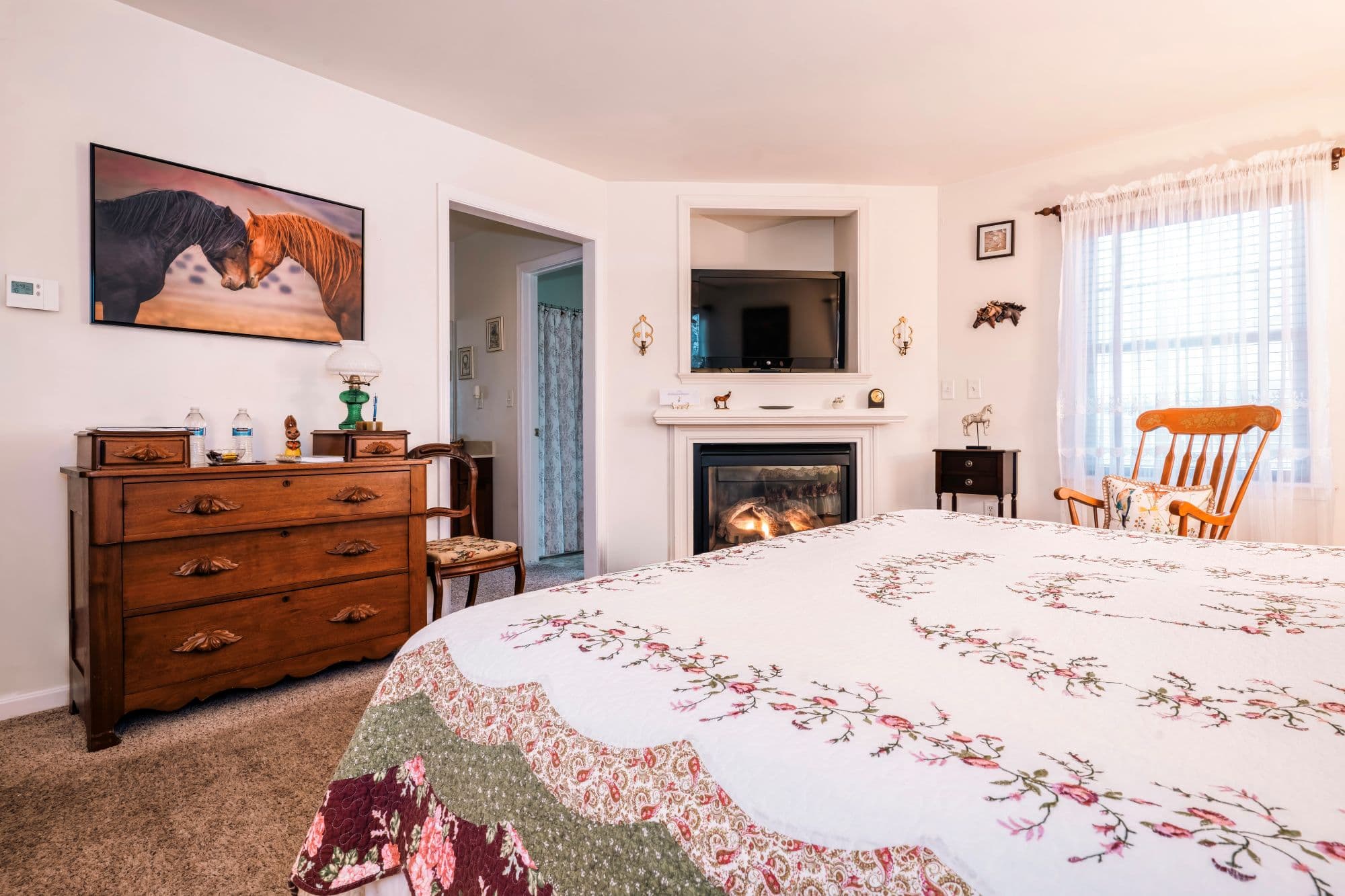 Cozy corner fireplace in a refined guest room with warm equestrian-inspired design