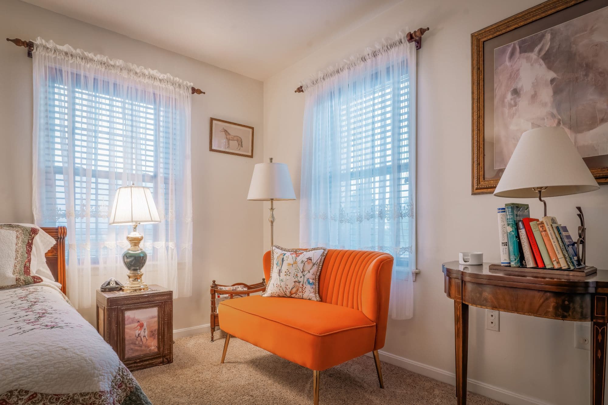 Relaxing seating area with orange sofa and windows in an elegant guest room