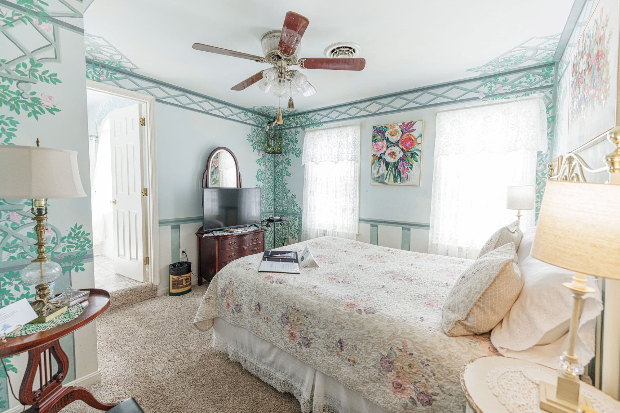 Queen bed in a cozy second-floor guest room with cottage-style décor and horse pasture views