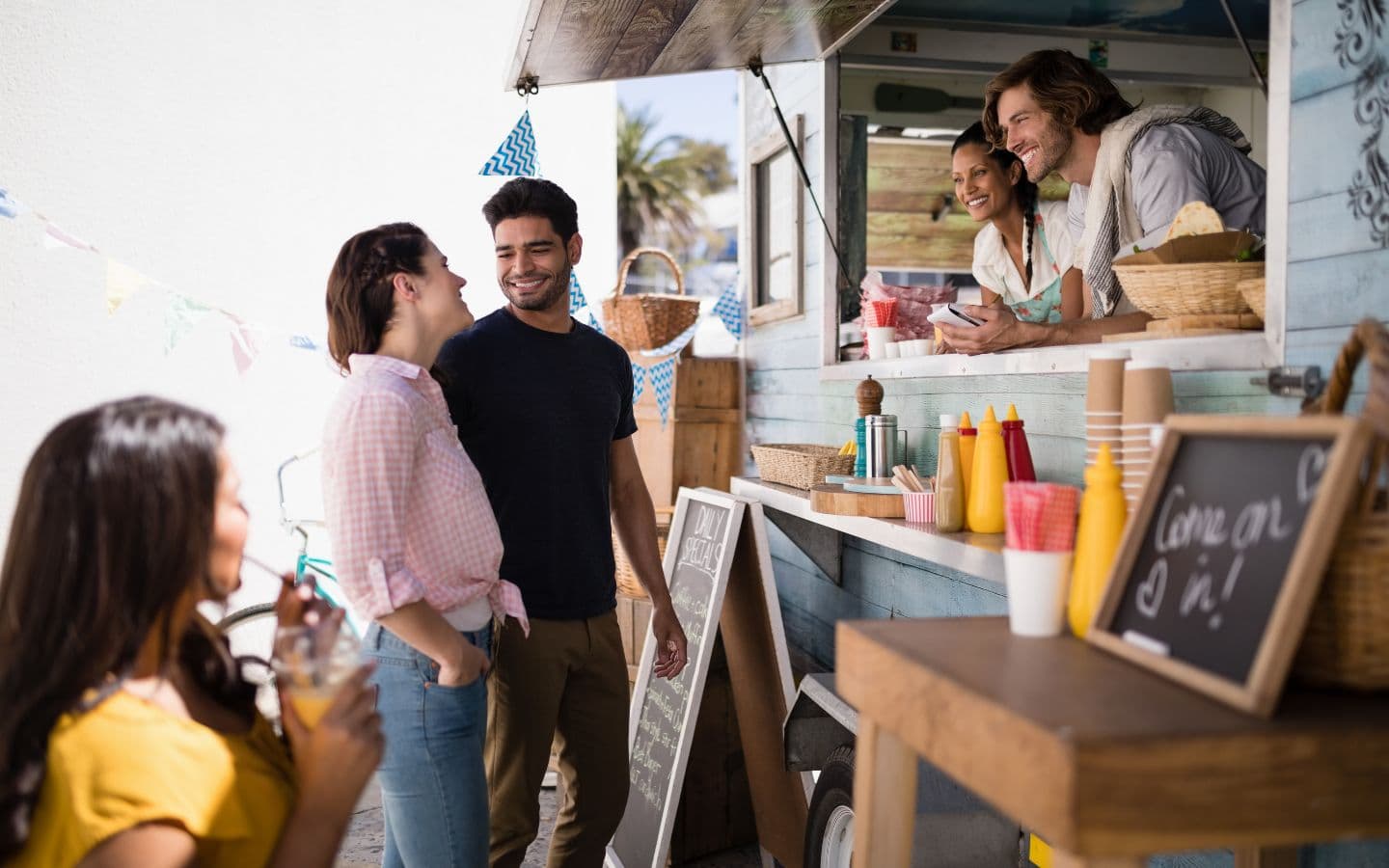 A group of friends enjoys food and drinks at a vibrant food truck.