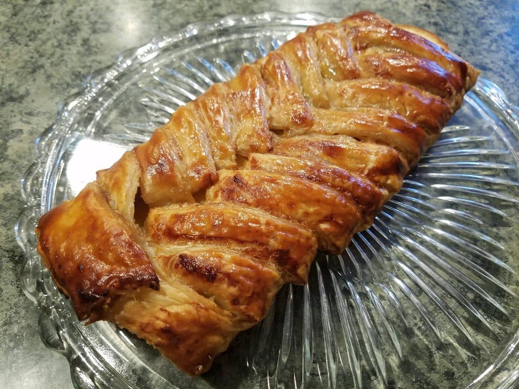 A golden-brown braided pastry on a glass plate.
