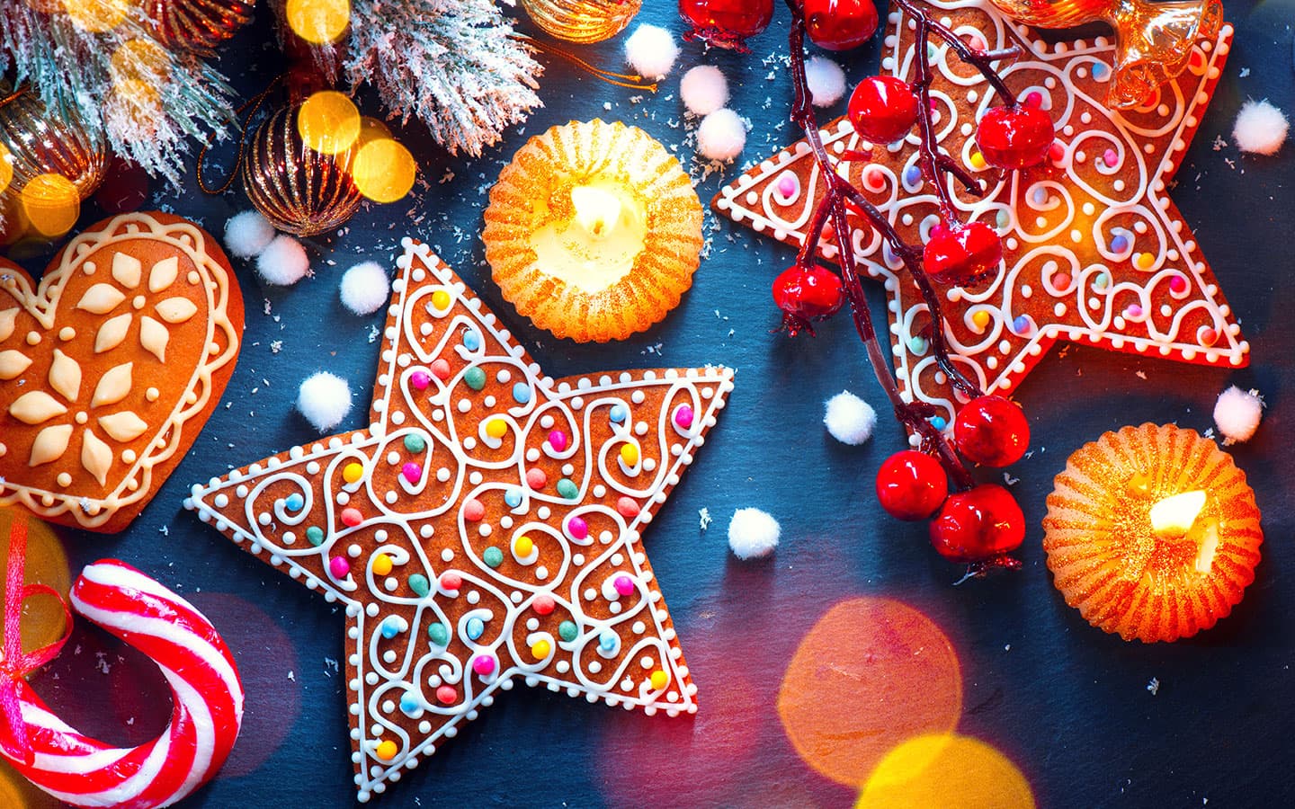 A festive arrangement of decorated gingerbread cookies, candles, and holiday decorations.