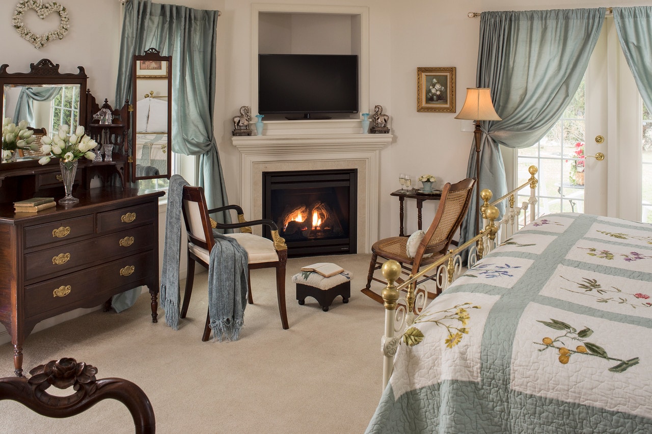 Dresser and chairs near fireplace by foot of bed