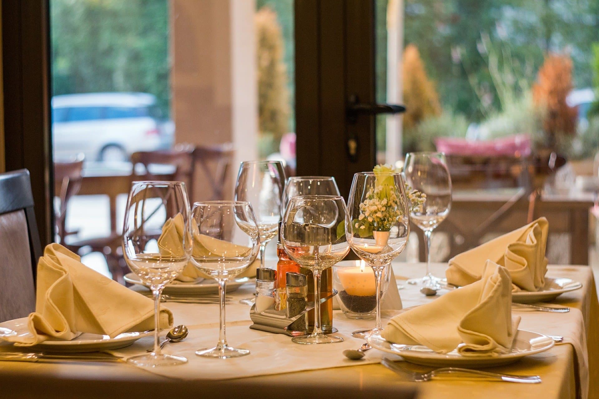 A beautifully set dining table with glassware and neatly folded napkins, illuminated by soft candlelight.