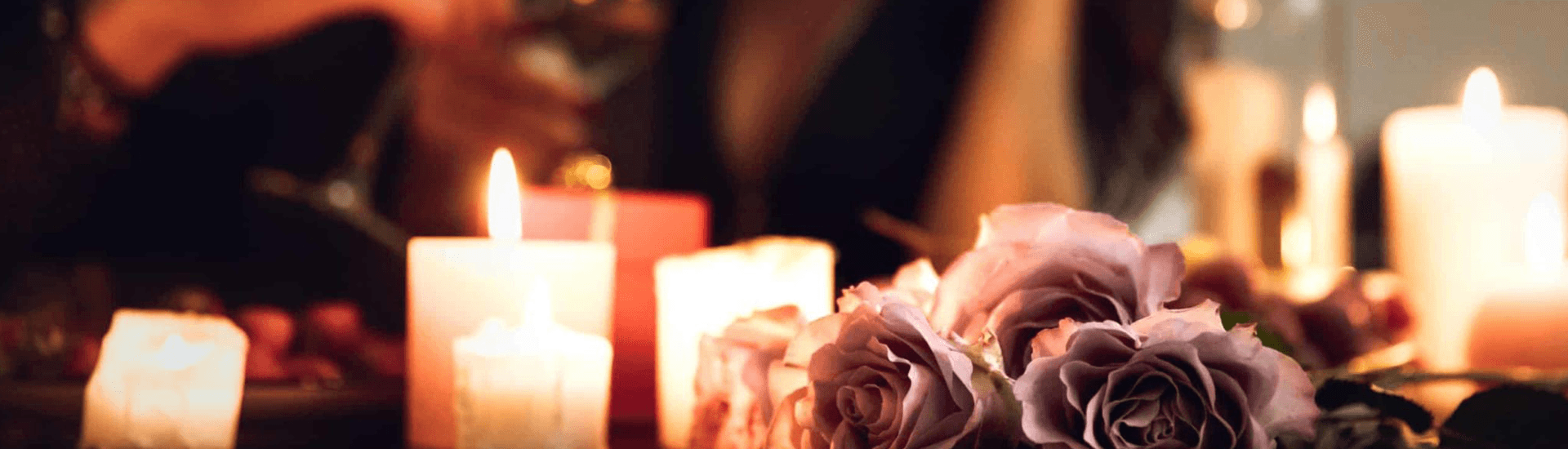 A soft, romantic setting featuring candles and pink roses.