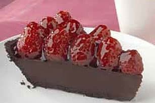 A slice of chocolate pie topped with glossy red strawberries.