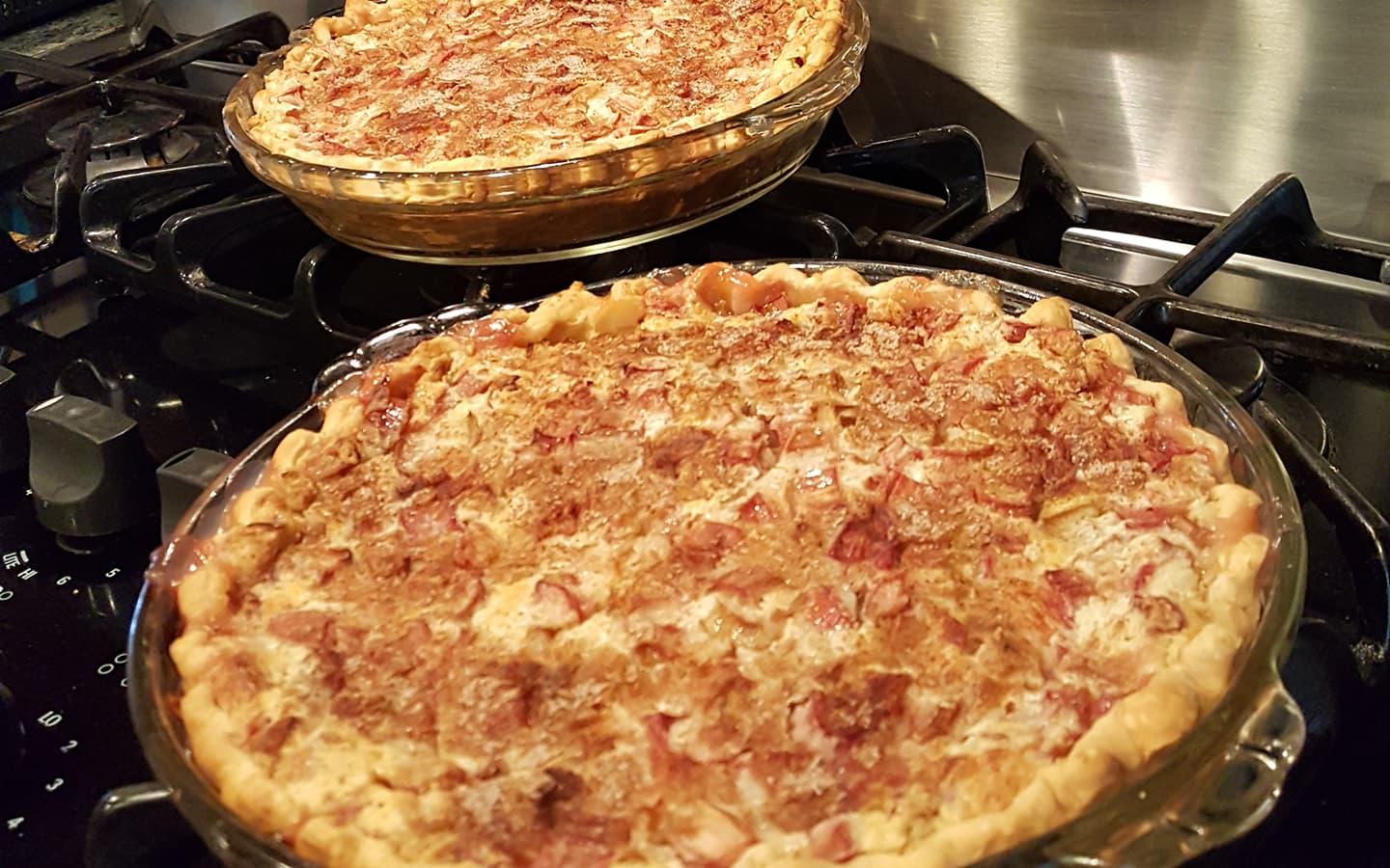 Two baked pies on a stovetop, one in the foreground and one in the background. Two baked pies on a stovetop, one in the foreground and one in the background.