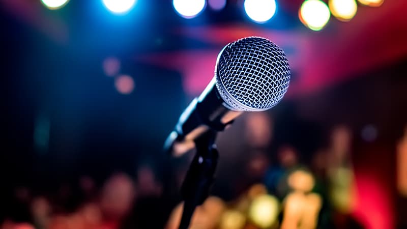 A close-up of a microphone in a brightly lit performance venue.