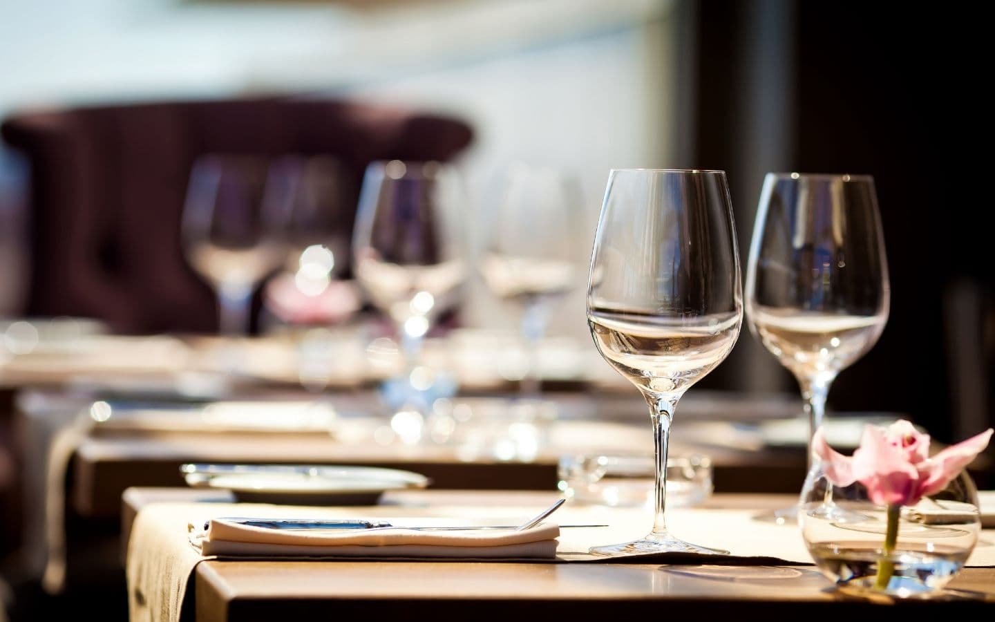 An elegant dining table set with wine glasses and a flower centerpiece.