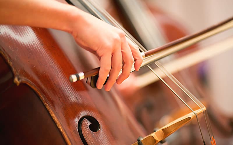 A hand holding a bow playing a cello.