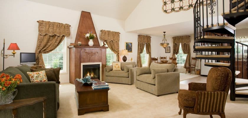 A cozy living room with a fireplace, elegant furniture, and a spiral staircase.