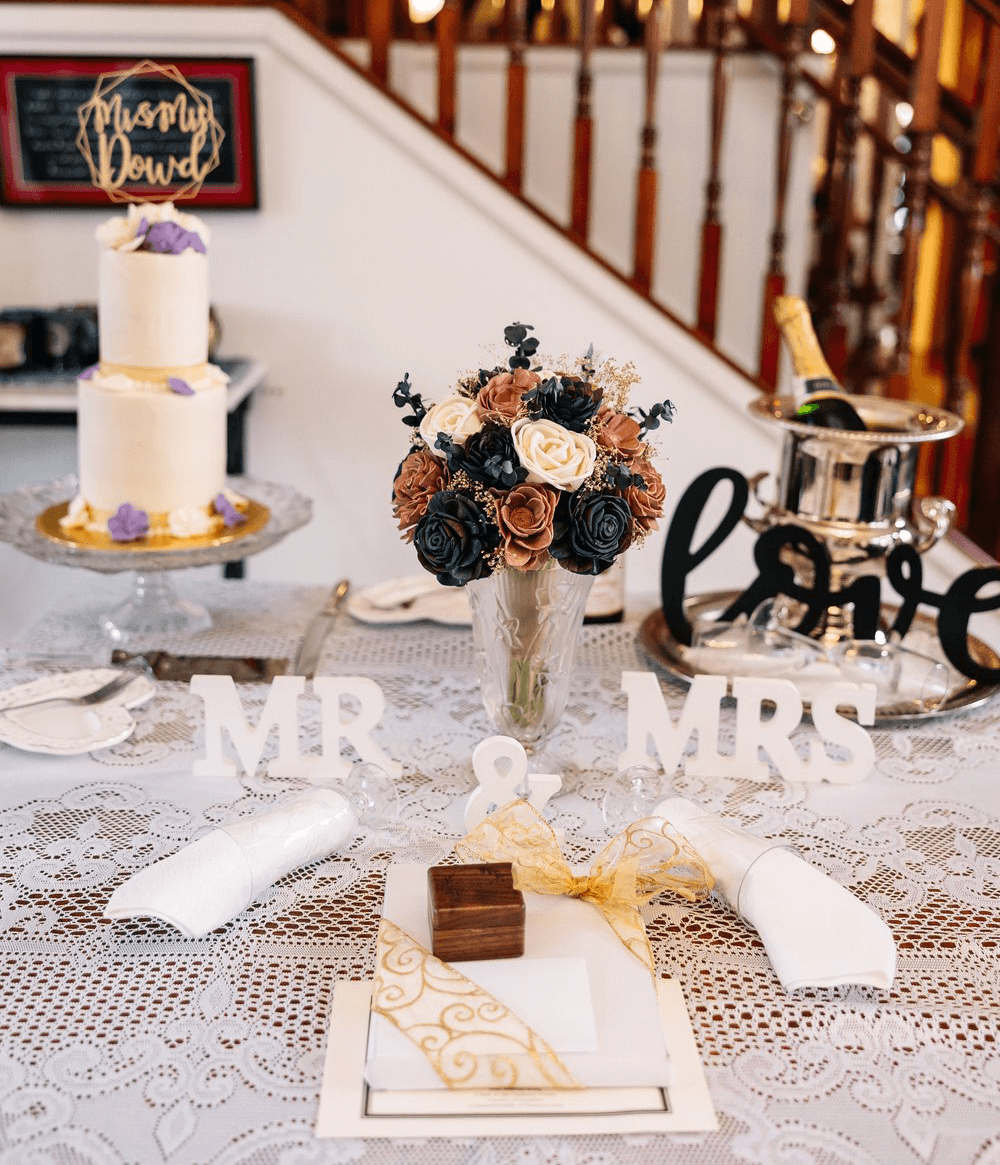 A beautifully arranged wedding table featuring a floral centerpiece, a tiered cake, and decor spelling "MR & MRS."