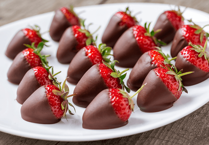 A plate of chocolate-covered strawberries arranged neatly.