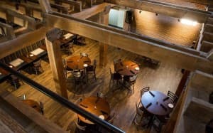 Aerial view of a wooden restaurant interior featuring circular tables and slatted seating.