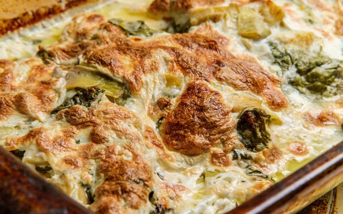 A golden-brown baked dish filled with creamy spinach and artichokes. A golden-brown baked dish filled with creamy spinach and artichokes.