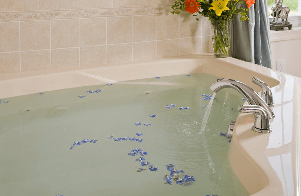 A serene jacuzzi with blue flower petals floating on the water's surface.