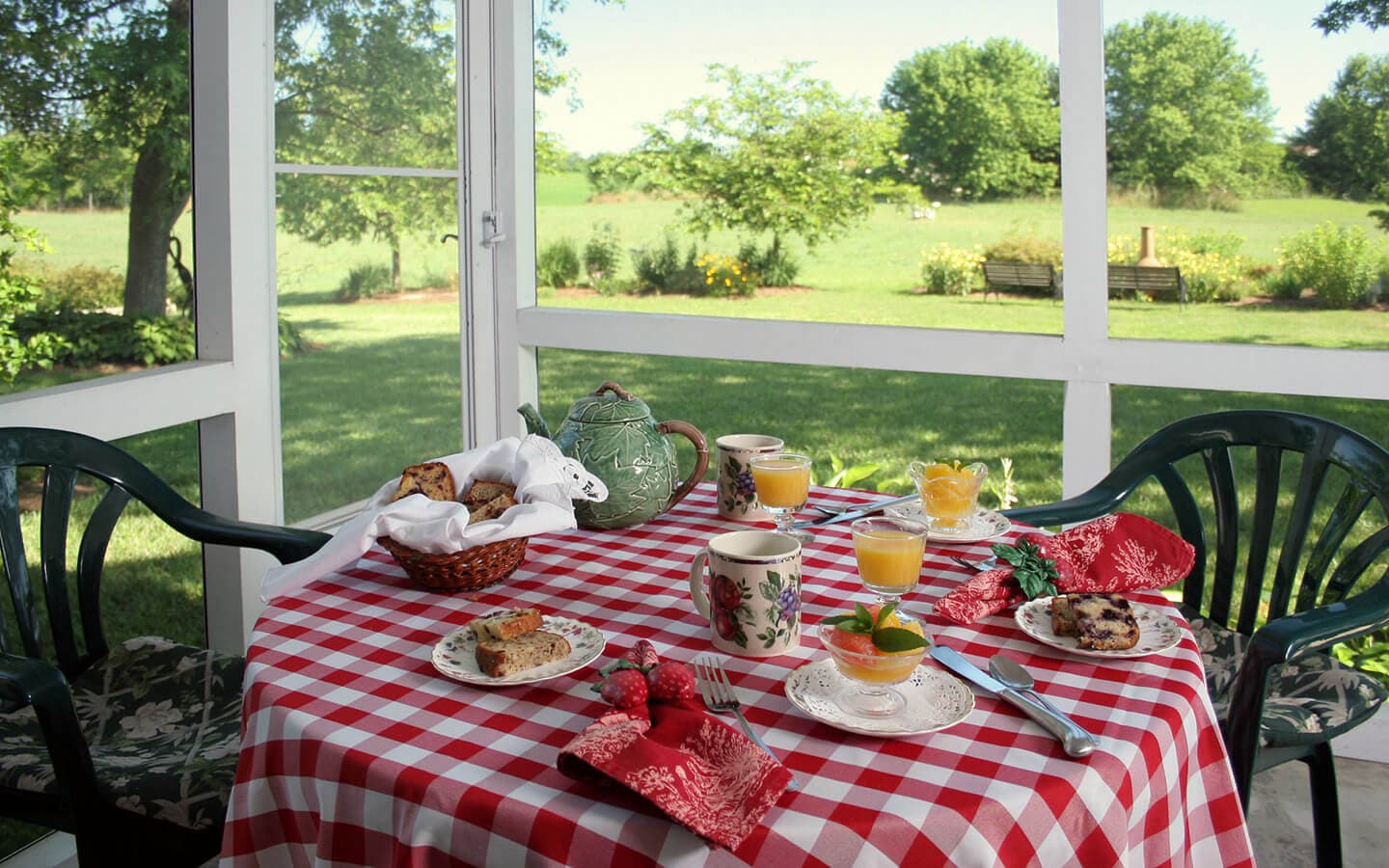 A cozy breakfast table set with food and drinks overlooks a green outdoor view.