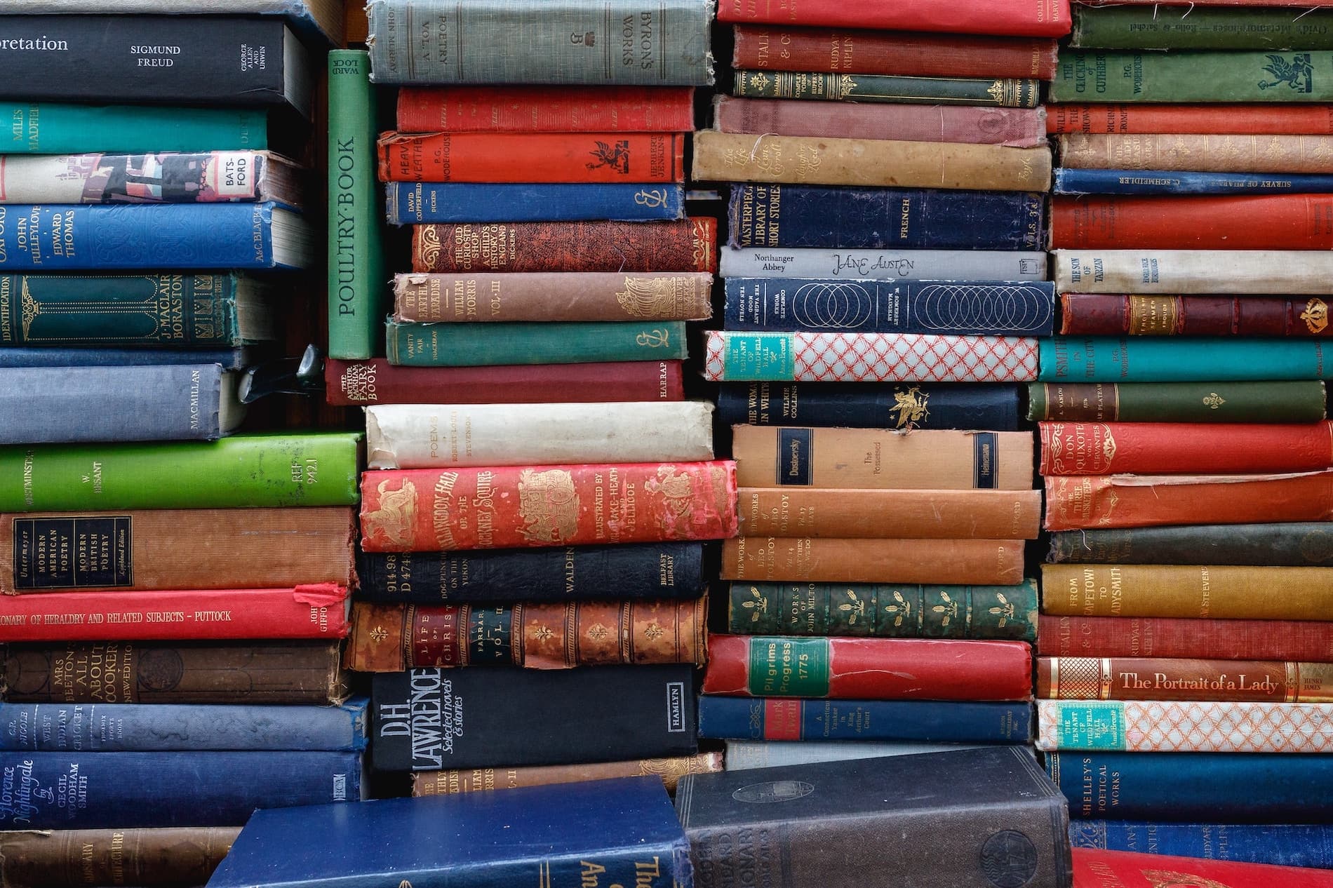 A close-up of stacked vintage books in various colors.