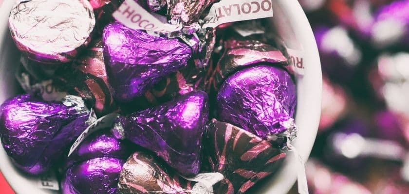 A close-up of purple-wrapped chocolate candies in a white bowl.