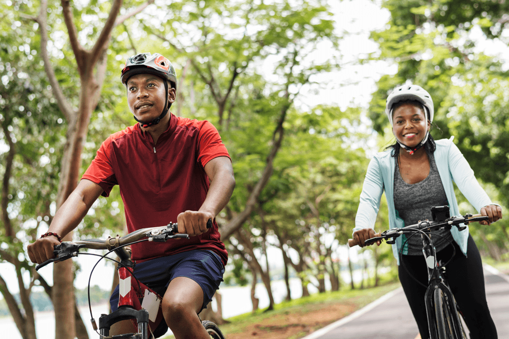 Two cyclists enjoying a ride on a tree-lined path.