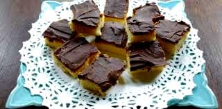 A plate of cut squares of dessert topped with chocolate frosting.