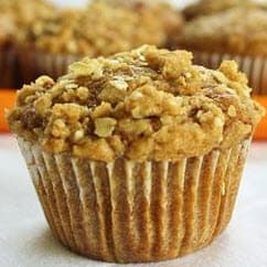 A close-up of a freshly baked muffin topped with crumbly oat streusel.