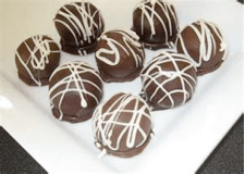 A plate of chocolate-covered dessert balls drizzled with white chocolate.