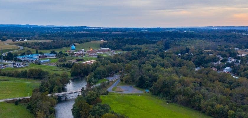 Aerial view of a lush landscape featuring a river, bridge, and a small town.