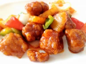 A plate of sweet and sour chicken with colorful vegetables.