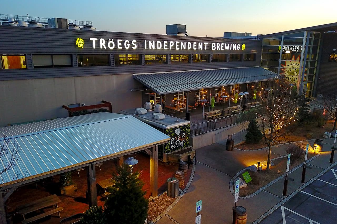 Exterior view of Tröegs Independent Brewing with outdoor seating and evening lights.