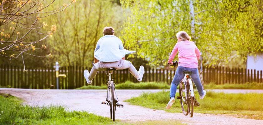 couple laughing and riding bikes near river area at park in springtime