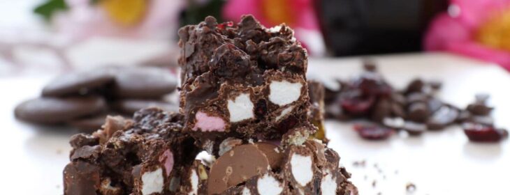 Dark chocolate clusters of rocky road candy, including white and pink marshmallows, nuts, and dried fruit.