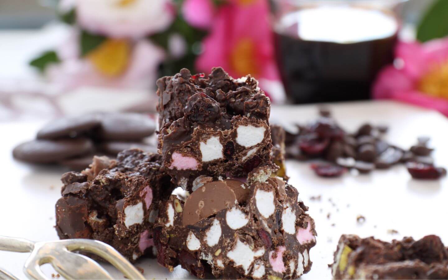 Dark chocolate clusters of rocky road candy, including white and pink marshmallows, nuts, and dried fruit.
