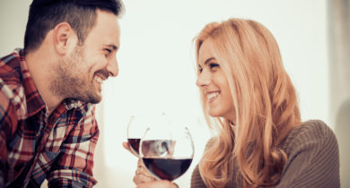 Couple smiles at each other over wine
