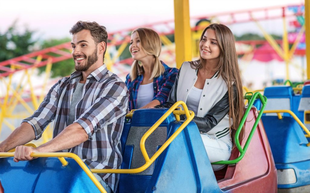 Man and two women smiling while riding in a roller coaster