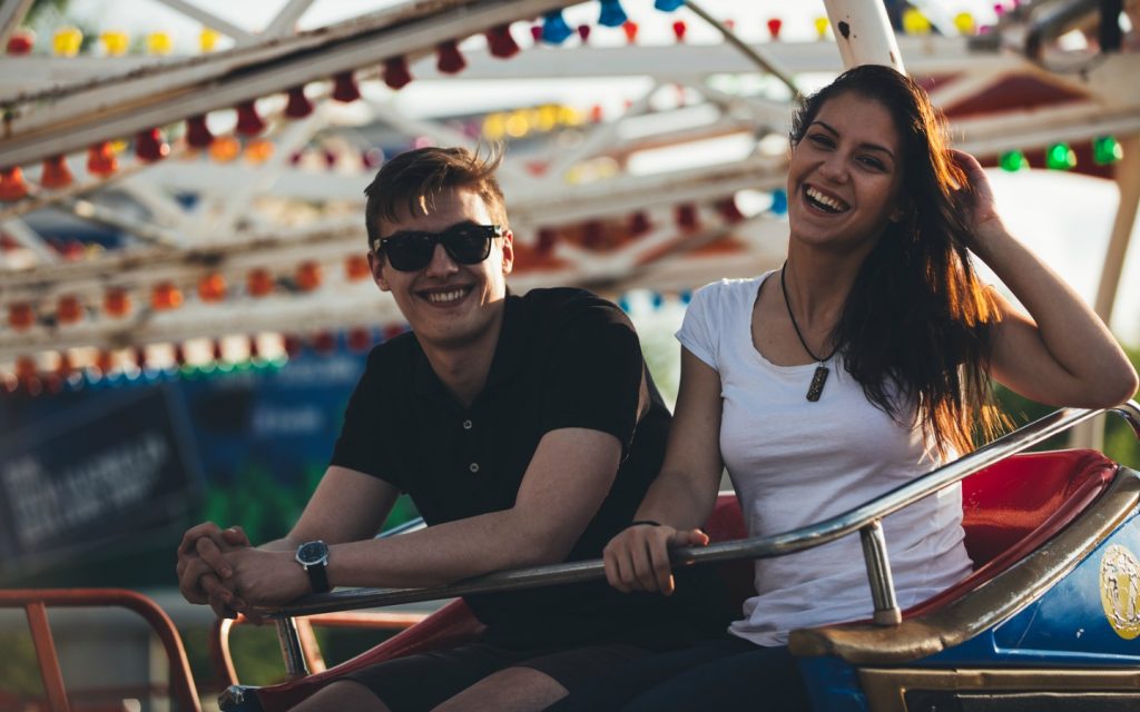 Man and woman smiling while sitting in a roller coaster