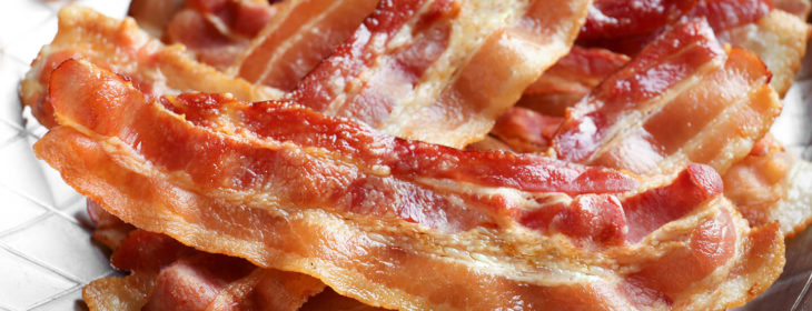 A large pile of bacon sits in a metal tray