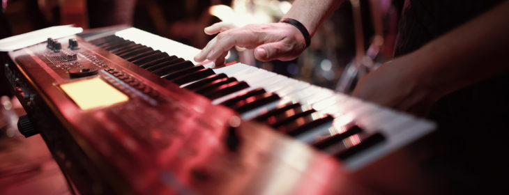 Hand playing keyboard on stage at a concert