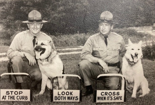 policemen kneeling by german shepherd dogs with instructional signs