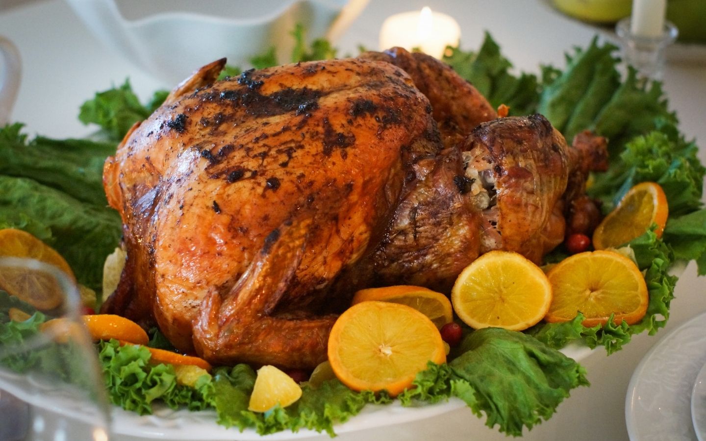 Golden brown, juicy roasted turkey surrounded by greenery and fresh orange slices